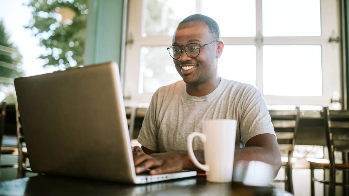 A man with a remote job sits in a coffee shop on his laptop